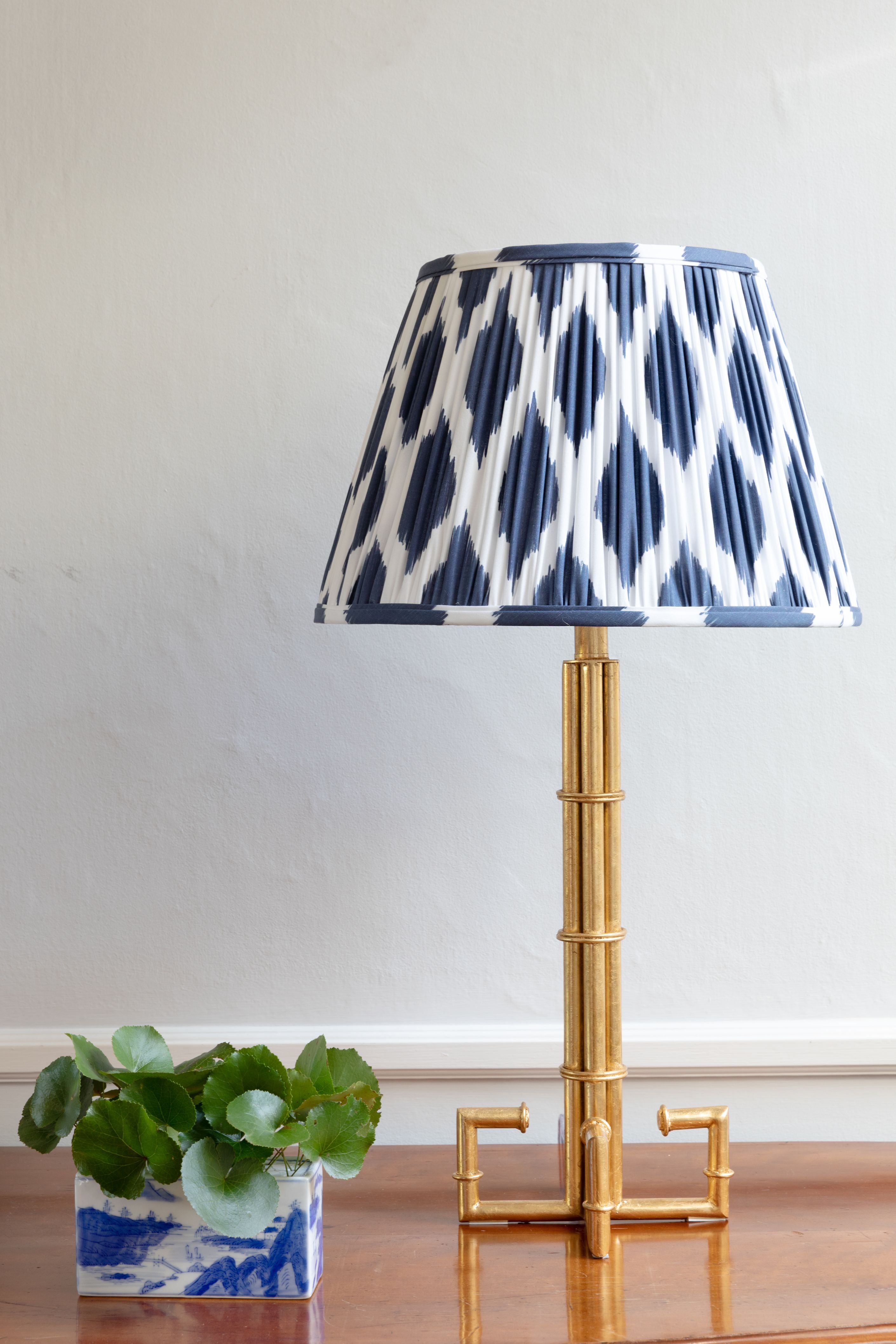 Navy blue patterned lamp shade on bronze stand.